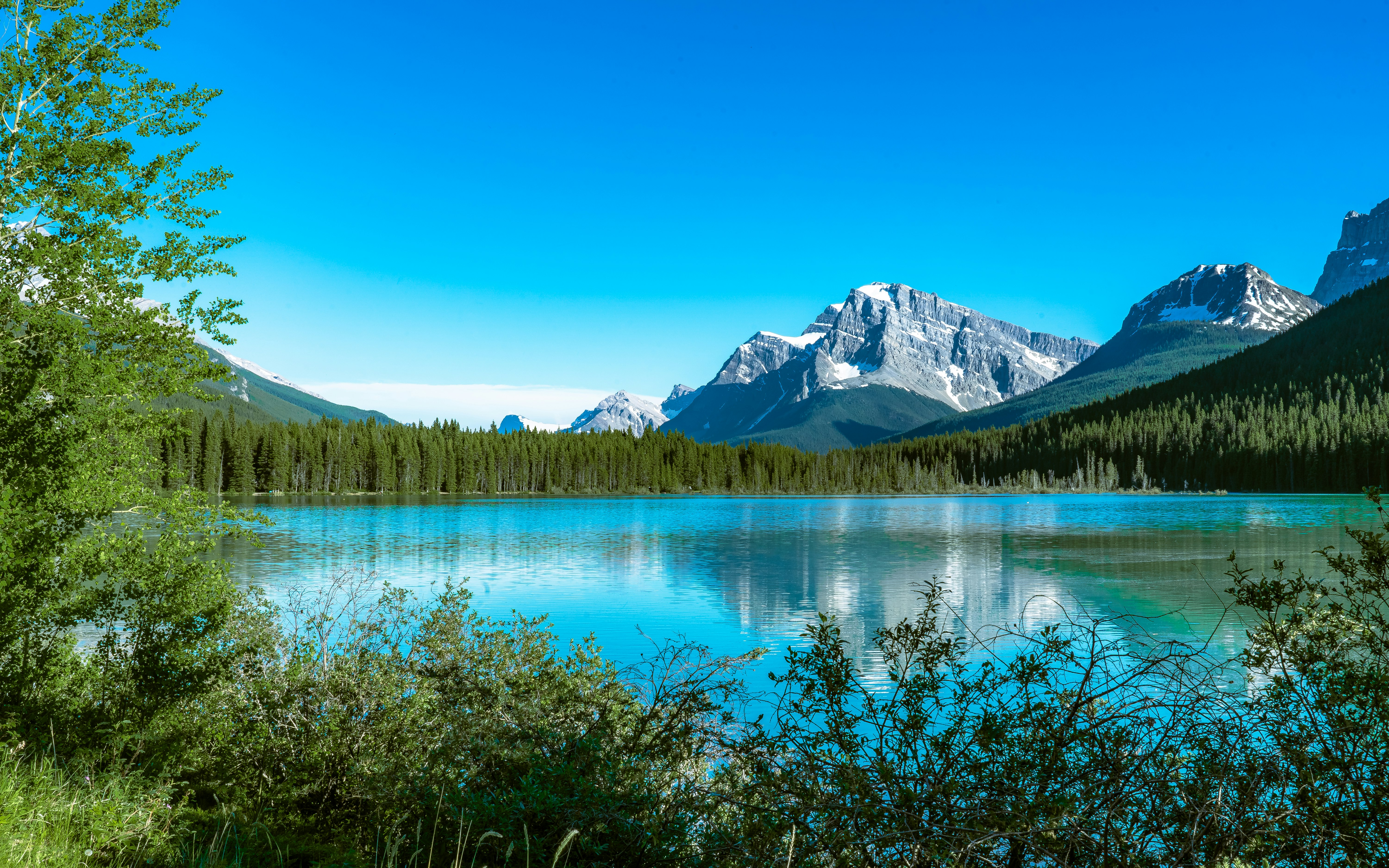 lake near snow covered mountain under blue sky during daytime